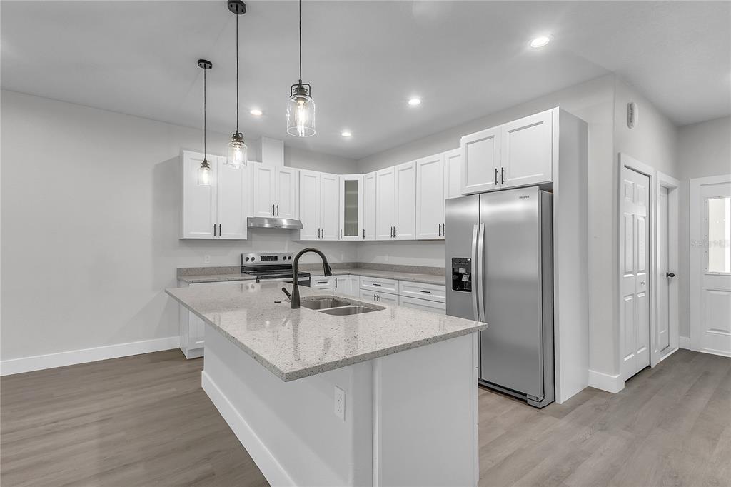 A modern kitchen features white cabinets, granite countertops, stainless steel appliances, and a central island — 6 EASTON PLACE, PALM COAST, FL