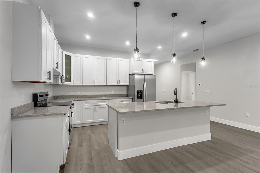 A modern kitchen features white cabinets, granite countertops, stainless steel appliances, and a central island — 6 EASTON PLACE, PALM COAST, FL