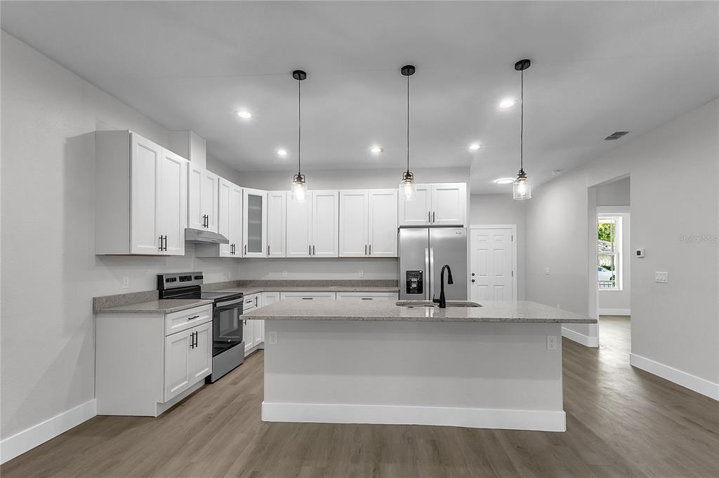 A modern kitchen features white cabinets, granite countertops, stainless steel appliances, and a central island — 6 EASTON PLACE, PALM COAST, FL