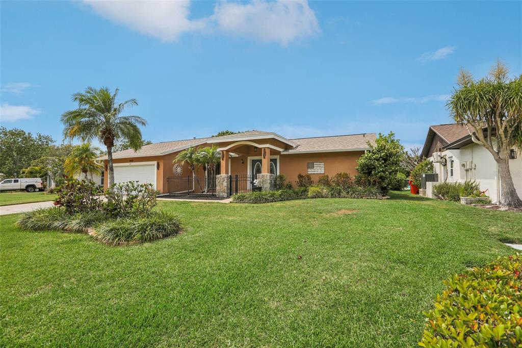 A single-story house with a tan exterior, a front porch, and a manicured lawn — 5916 OAKHURST DRIVE, SEMINOLE, FL
