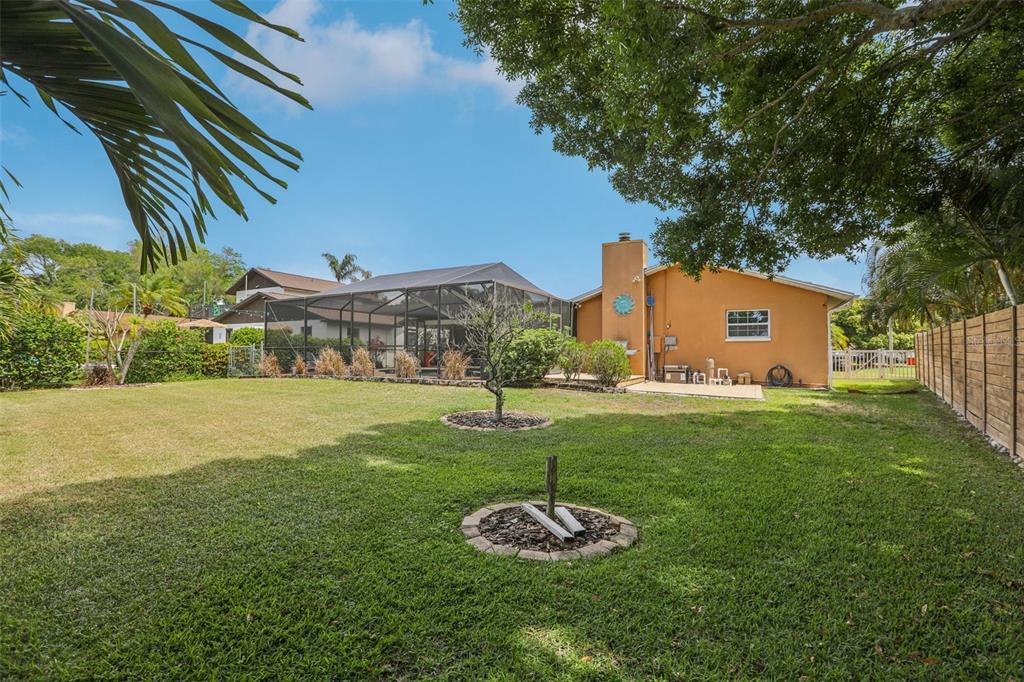 A backyard with a screened-in pool enclosure, a tan house, and a small fire pit — 5916 OAKHURST DRIVE, SEMINOLE, FL