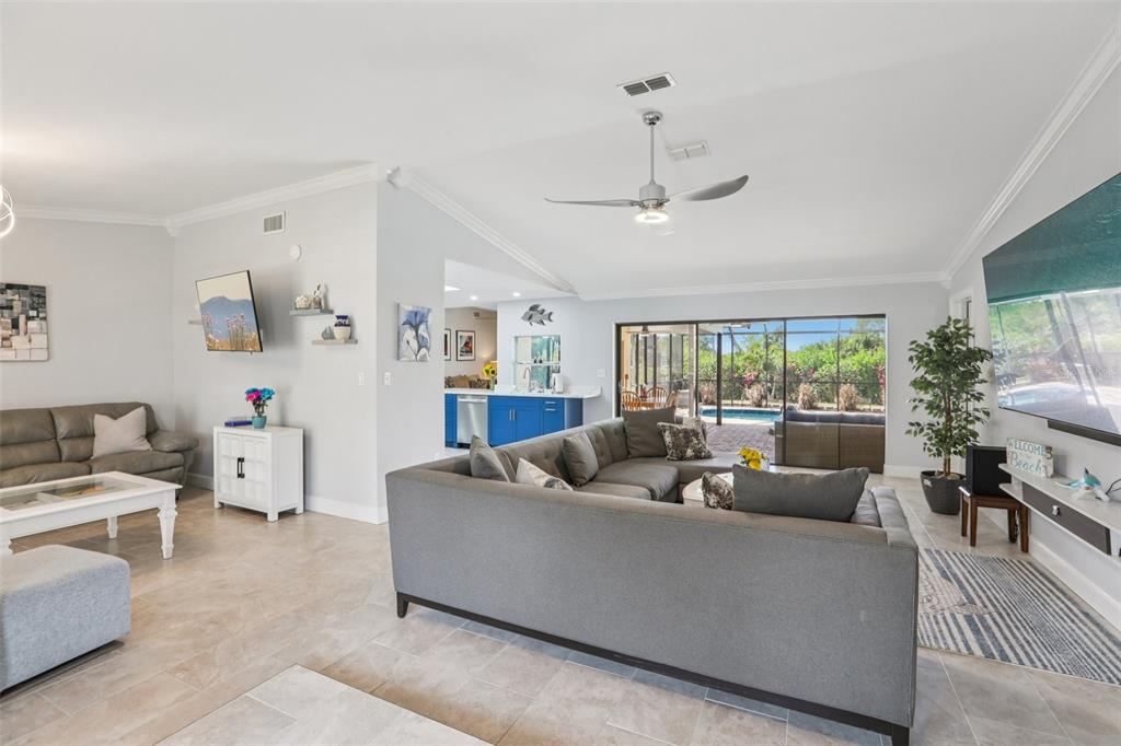 A spacious living room features a large sectional sofa, tile flooring, and a sliding glass door — 5916 OAKHURST DRIVE, SEMINOLE, FL