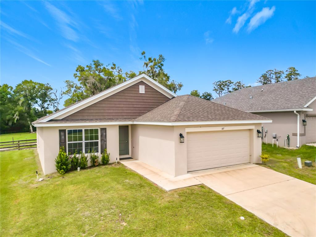 A single-story house with a beige stucco exterior, brown siding, and an attached two-car garage — 187 NW 45TH LOOP, OCALA, FL
