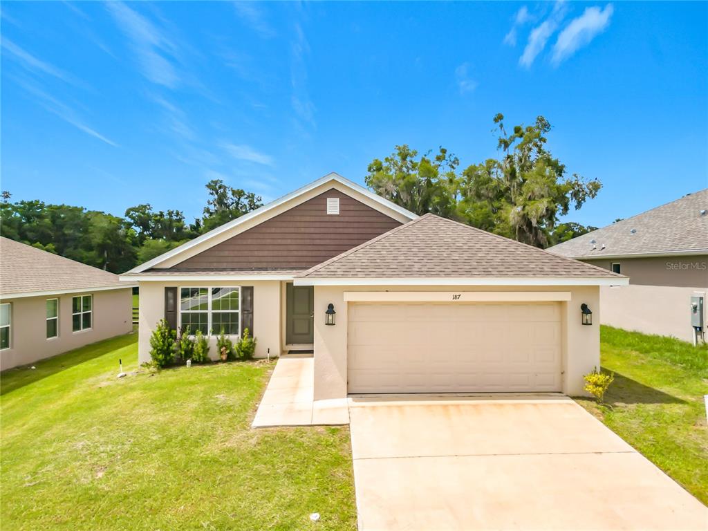 A single-story house with a beige stucco exterior, brown siding, and a two-car garage — 187 NW 45TH LOOP, OCALA, FL