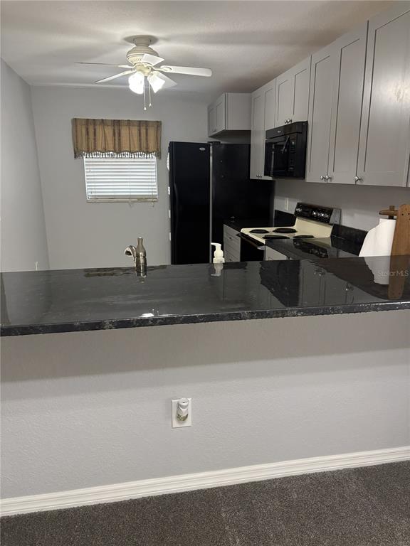 A kitchen features gray cabinets, black appliances, and a dark countertop breakfast bar — 175 KINGS HIGHWAY UNIT A1, PUNTA GORDA, FL
