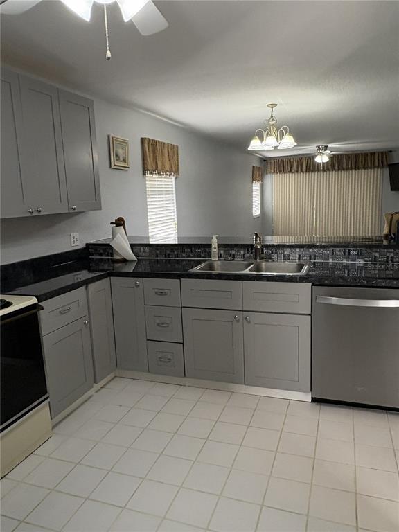 A kitchen features gray cabinets, dark countertops, a double sink, and white tiled flooring — 175 KINGS HIGHWAY UNIT A1, PUNTA GORDA, FL
