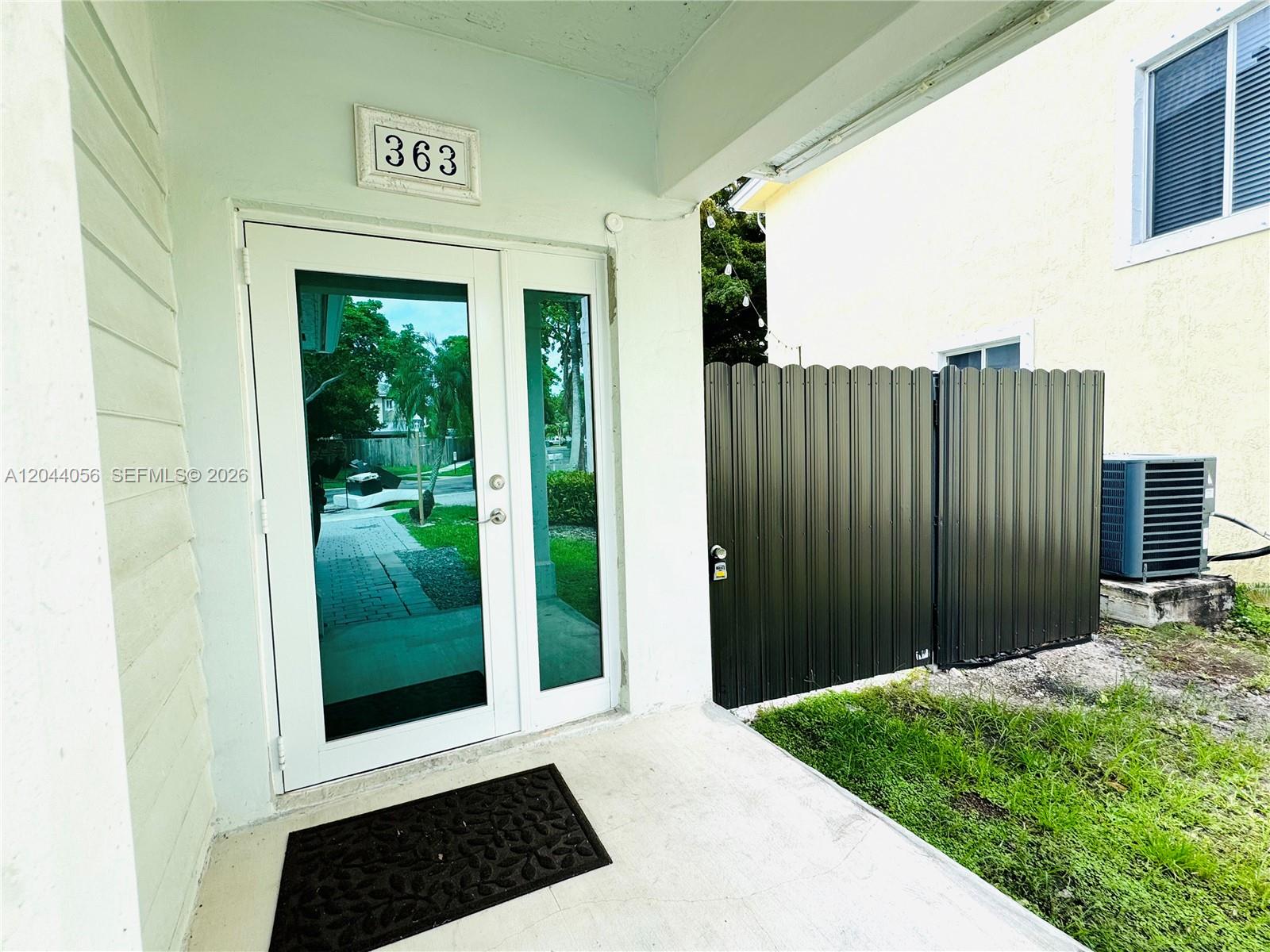 A white front door with a side window and a black metal privacy fence — 363 NE 35th Ter, Homestead FL 33033, HOMESTEAD, FL