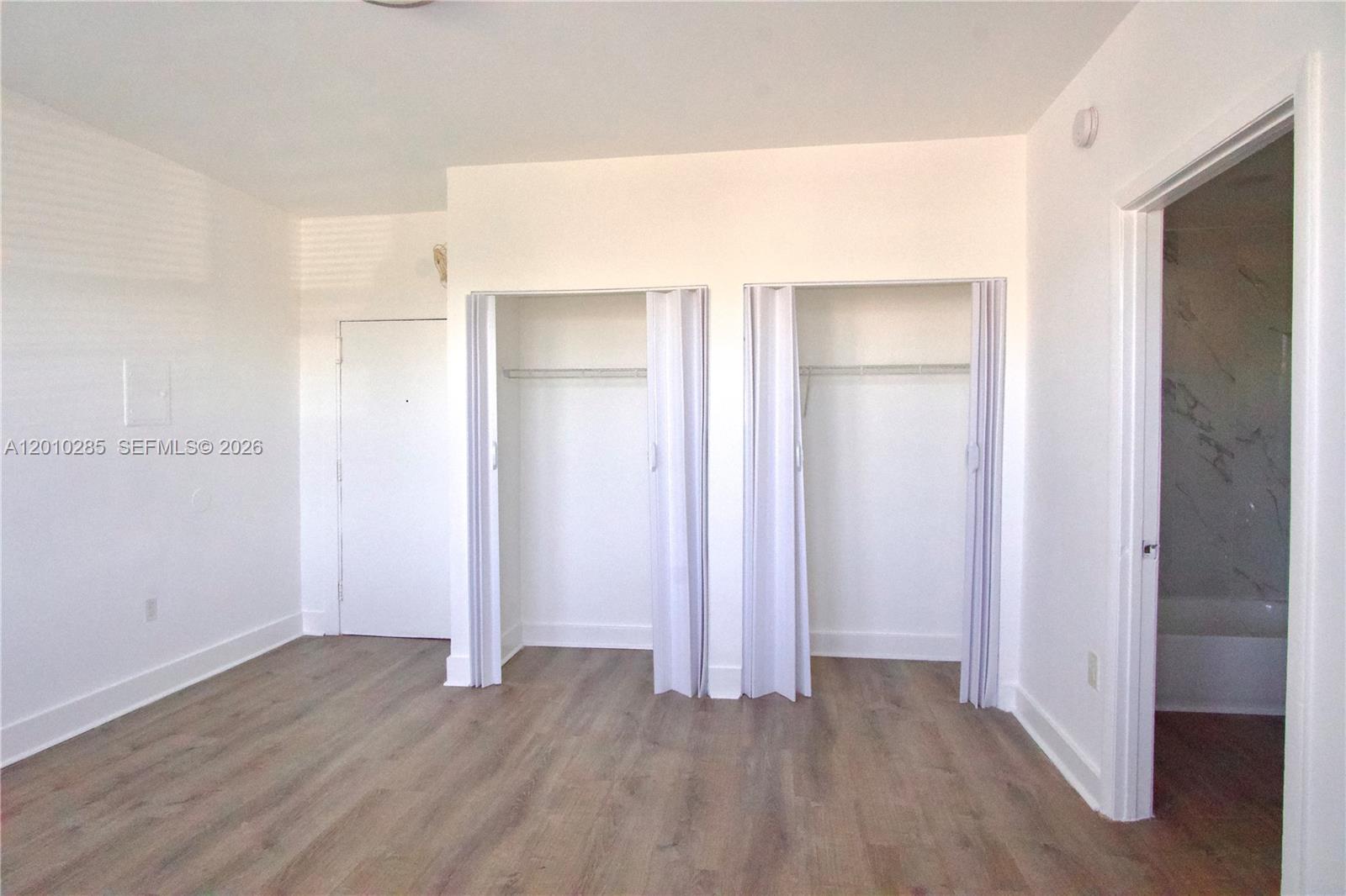 This bedroom features light wood-look flooring, two closets with folding doors, and an attached bathroom — 501 SW 6th Ct # 322, Miami FL 33130, MIAMI, FL