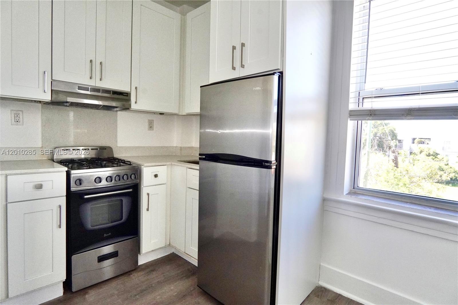A kitchen features white cabinets, stainless steel appliances, and a window with blinds — 501 SW 6th Ct # 322, Miami FL 33130, MIAMI, FL