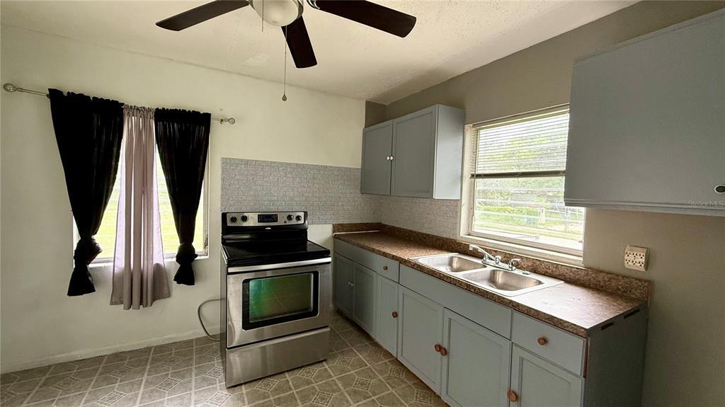 A kitchen features light blue cabinets, a stainless steel stove, and a double-basin sink — 202 E POLK STREET, AUBURNDALE, FL