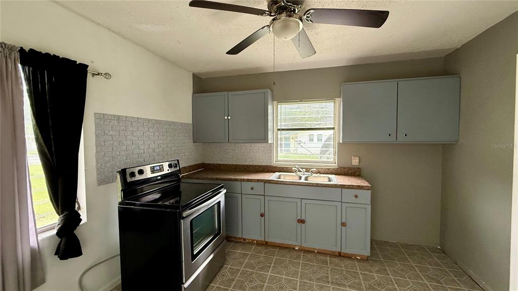 A kitchen features light blue cabinets, a black stove, and a double-basin sink — 202 E POLK STREET, AUBURNDALE, FL