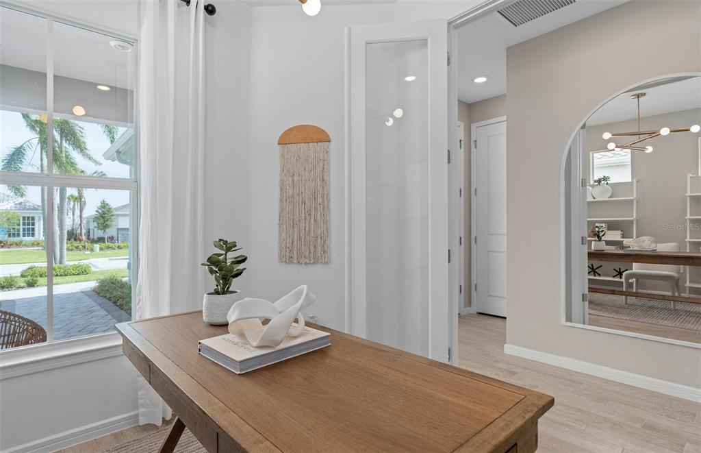 A home office features a wooden desk, a wall-mounted macramé decoration, and an arched mirror — 6760 SUNRISE COVE DRIVE, CLERMONT, FL