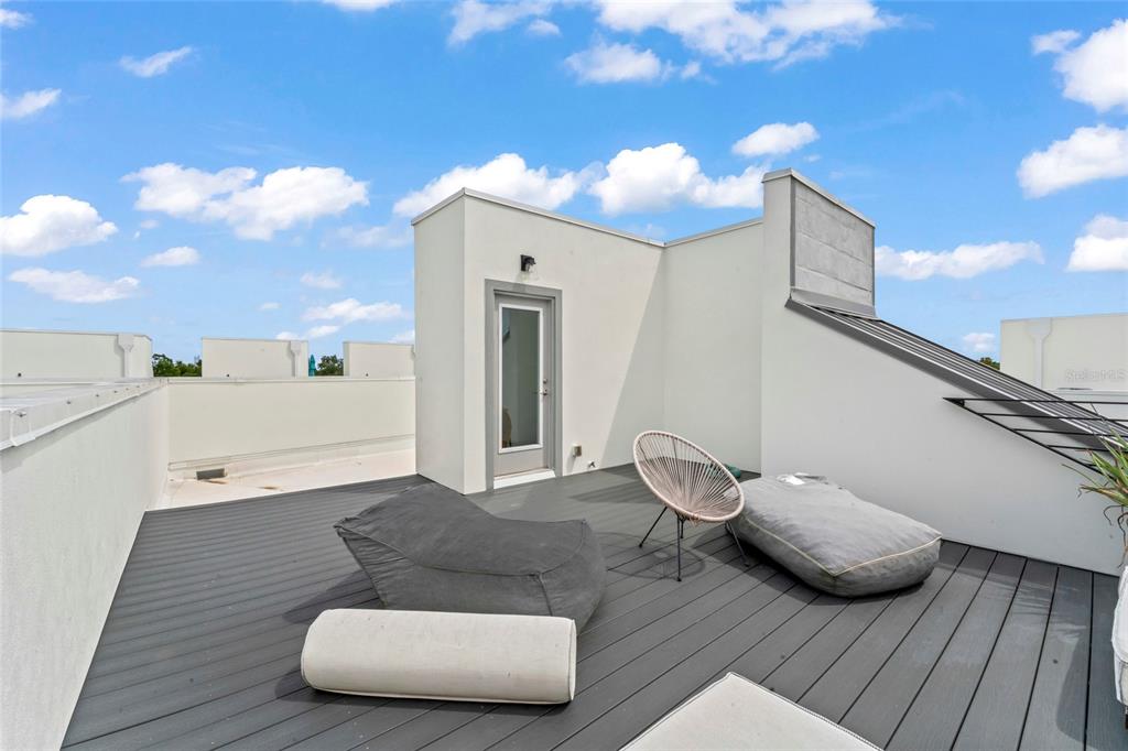 A rooftop deck features dark gray composite decking, a modern chair, and casual floor seating — 2621 1ST AVENUE N UNIT 19, ST PETERSBURG, FL