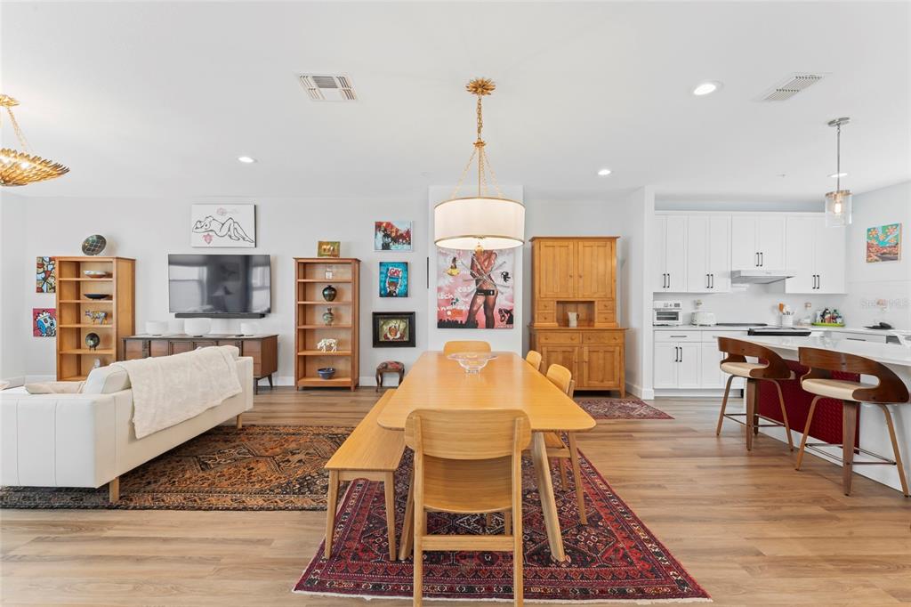 A bright open-concept living and dining area features wood flooring, white cabinetry, and eclectic artwork — 2621 1ST AVENUE N UNIT 19, ST PETERSBURG, FL