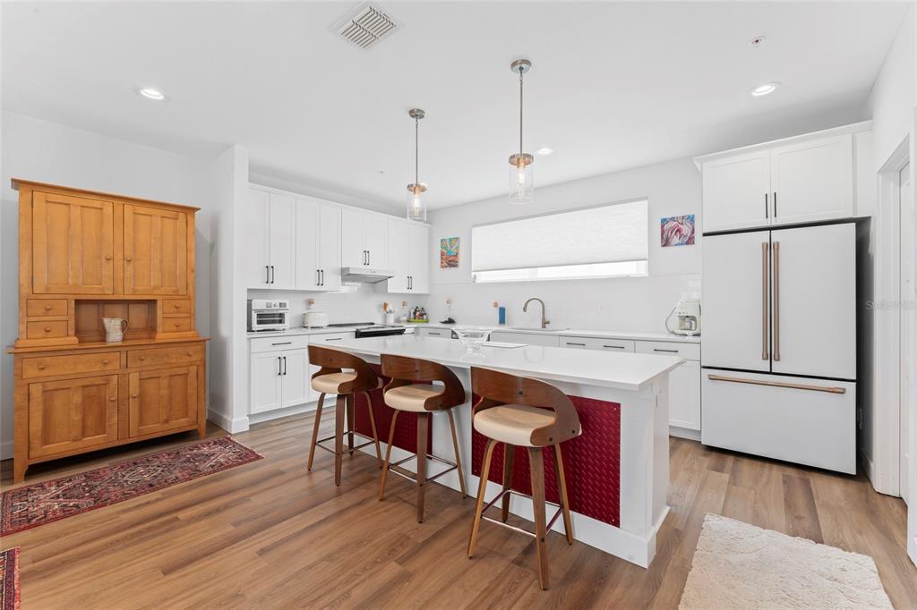 A kitchen features white cabinets, a white island with three stools, and a wooden hutch — 2621 1ST AVENUE N UNIT 19, ST PETERSBURG, FL