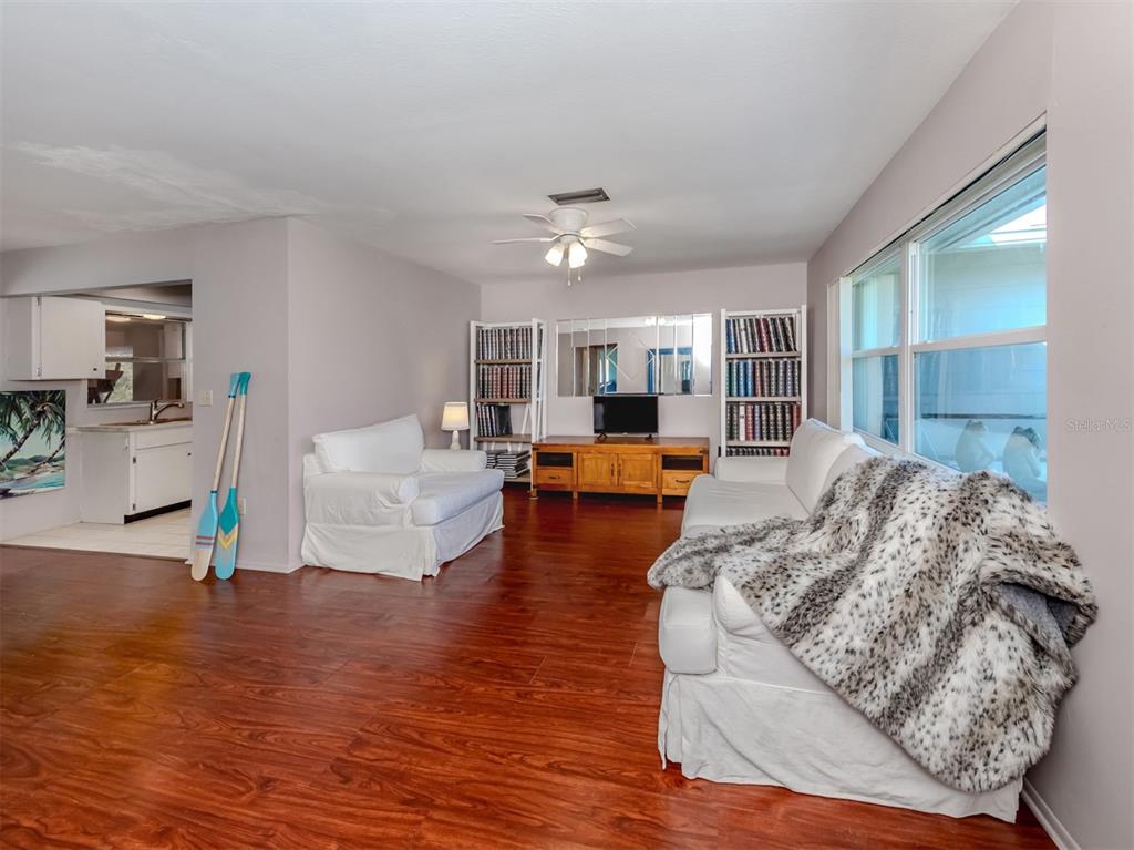 A living room features wood-look flooring, white sofas, bookshelves, and a ceiling fan — 424 CENTER ROAD, VENICE, FL