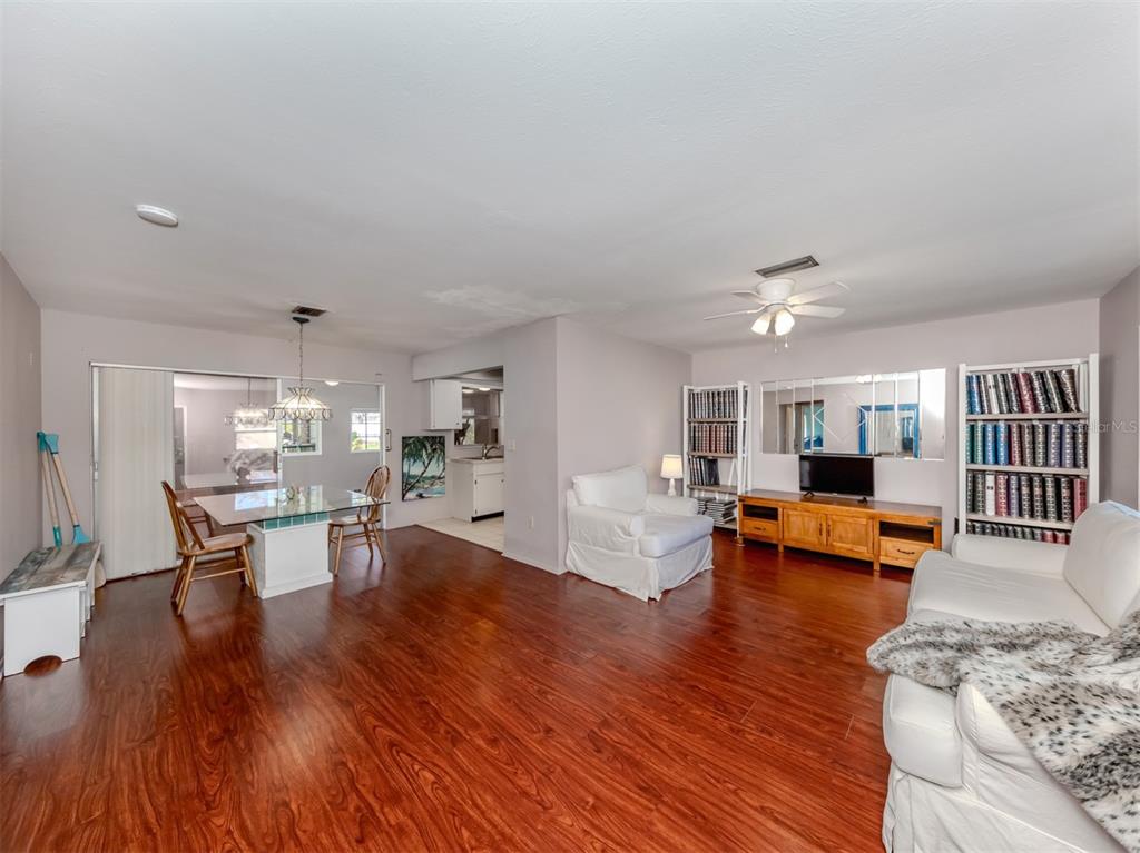 A living and dining area with wood-look flooring, white furniture, and a glass-topped dining table — 424 CENTER ROAD, VENICE, FL