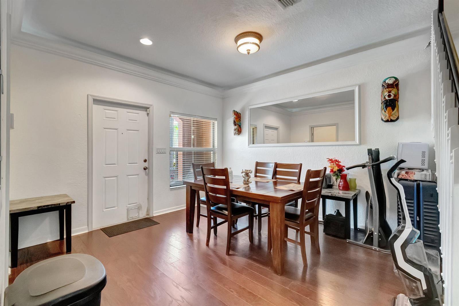A dining room with a wooden table, chairs, a large wall mirror, and hardwood flooring — 103 Monterey Bay Drive, Boynton Beach FL 33426, BOYNTON BEACH, FL