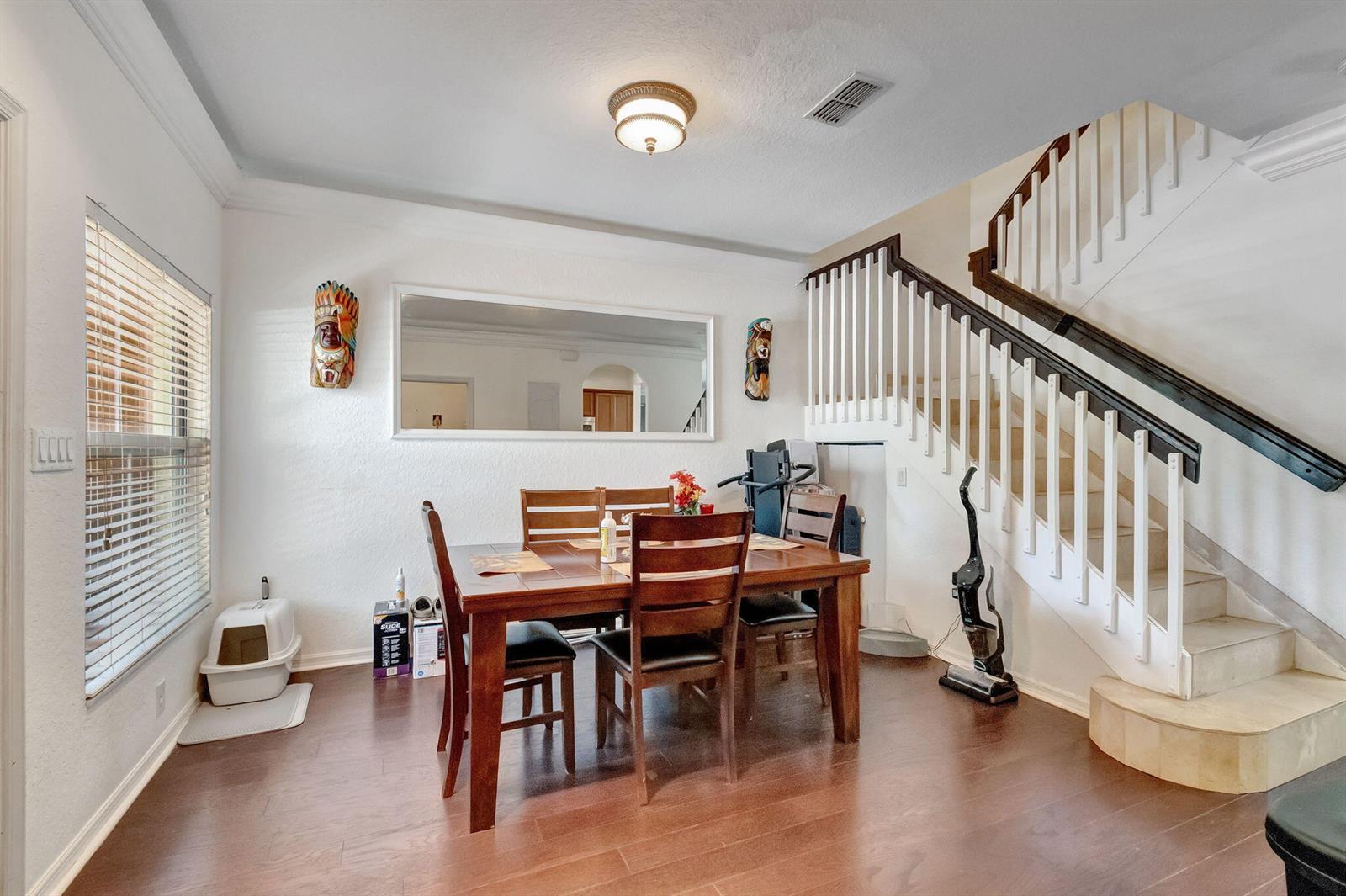 A dining room with a wooden table, chairs, a staircase, and a large wall mirror — 103 Monterey Bay Drive, Boynton Beach FL 33426, BOYNTON BEACH, FL
