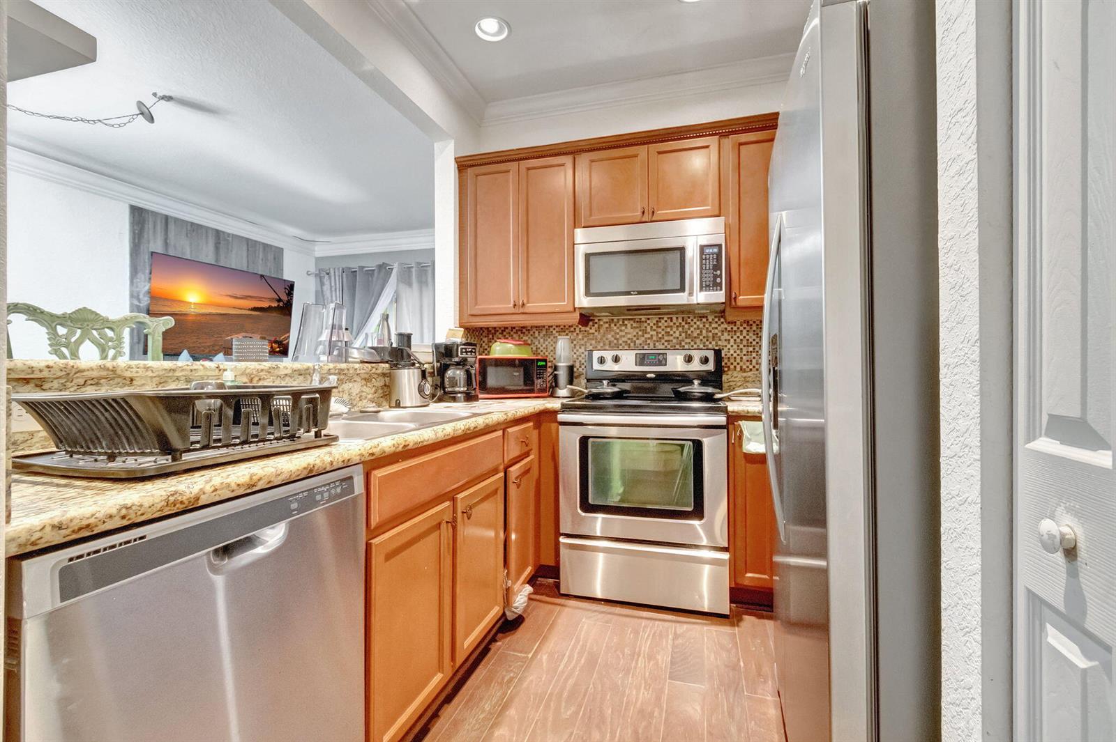 A kitchen with wood cabinets, stainless steel appliances, and granite countertops — 103 Monterey Bay Drive, Boynton Beach FL 33426, BOYNTON BEACH, FL