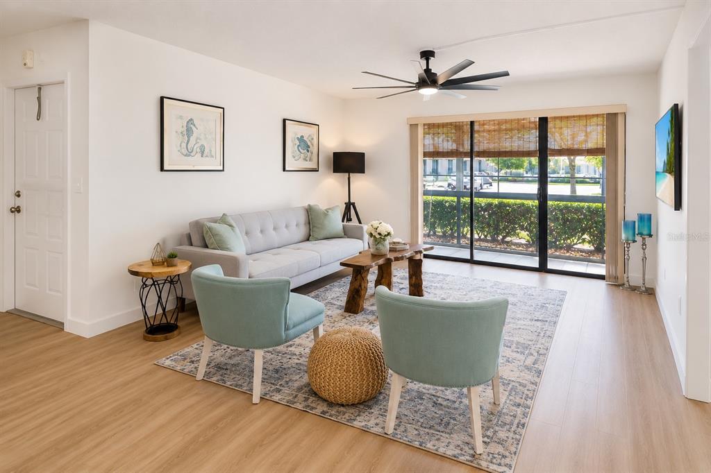 A living room features a gray sofa, two teal armchairs, and a wooden coffee table — 3211 LAKE PINE WAY E UNIT A1, TARPON SPRINGS, FL