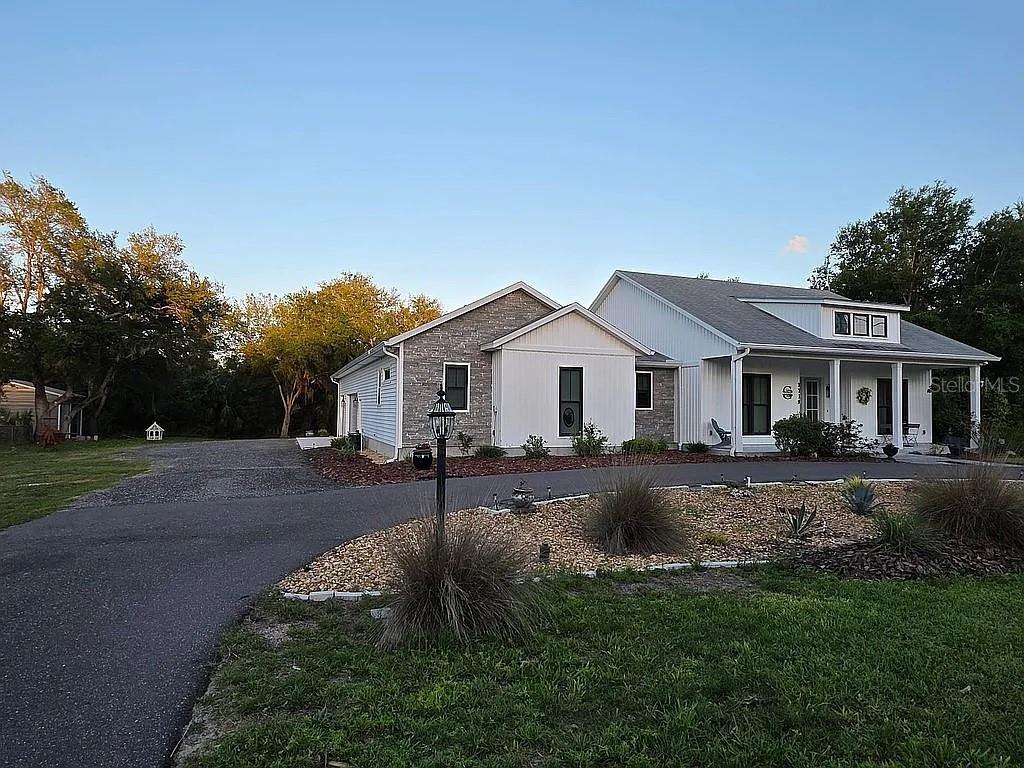 A single-story house with stone and white siding features a paved driveway and landscaping — 2719 BROOKLINE AVENUE, NEW SMYRNA BEACH, FL