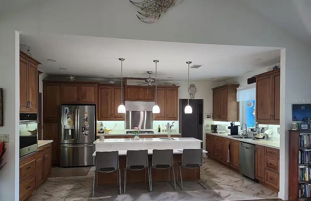 A kitchen features wood cabinets, a central island with seating, and stainless steel appliances — 2719 BROOKLINE AVENUE, NEW SMYRNA BEACH, FL