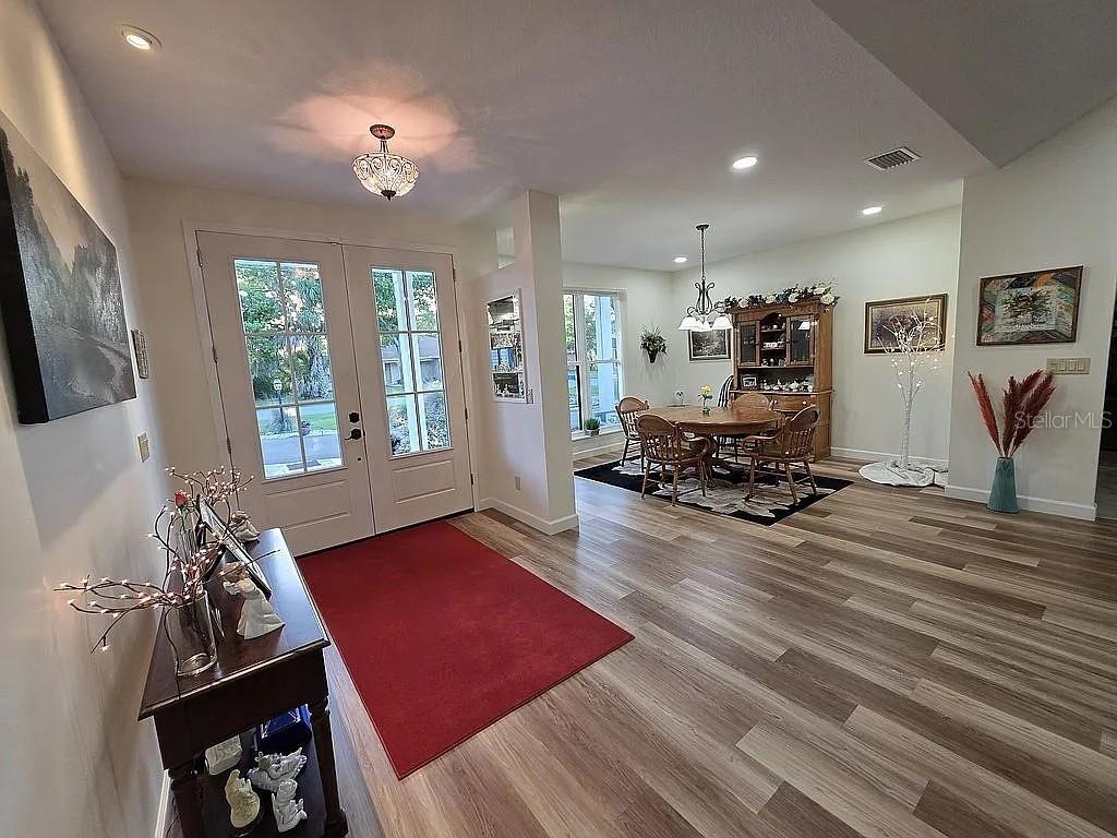 A foyer with a red rug leads into a dining room with wood-look flooring — 2719 BROOKLINE AVENUE, NEW SMYRNA BEACH, FL