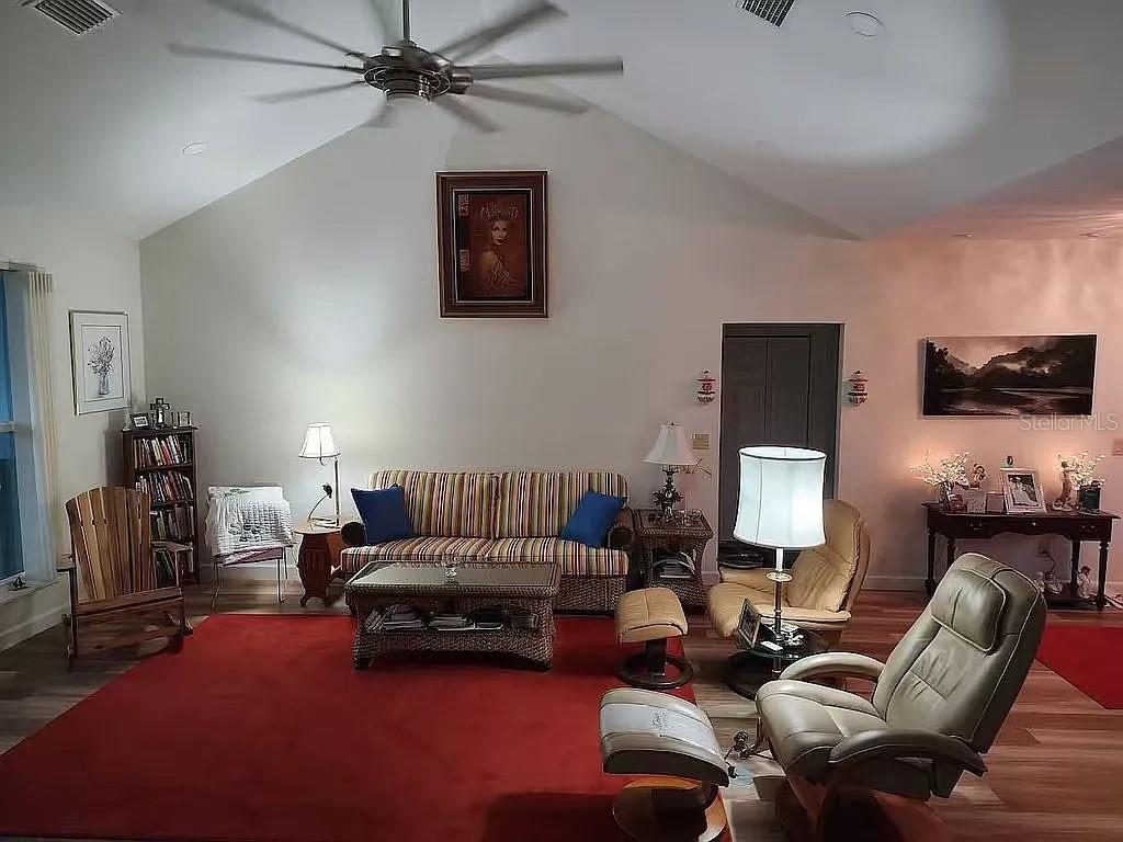 A living room features a vaulted ceiling, a red area rug, and assorted seating furniture — 2719 BROOKLINE AVENUE, NEW SMYRNA BEACH, FL