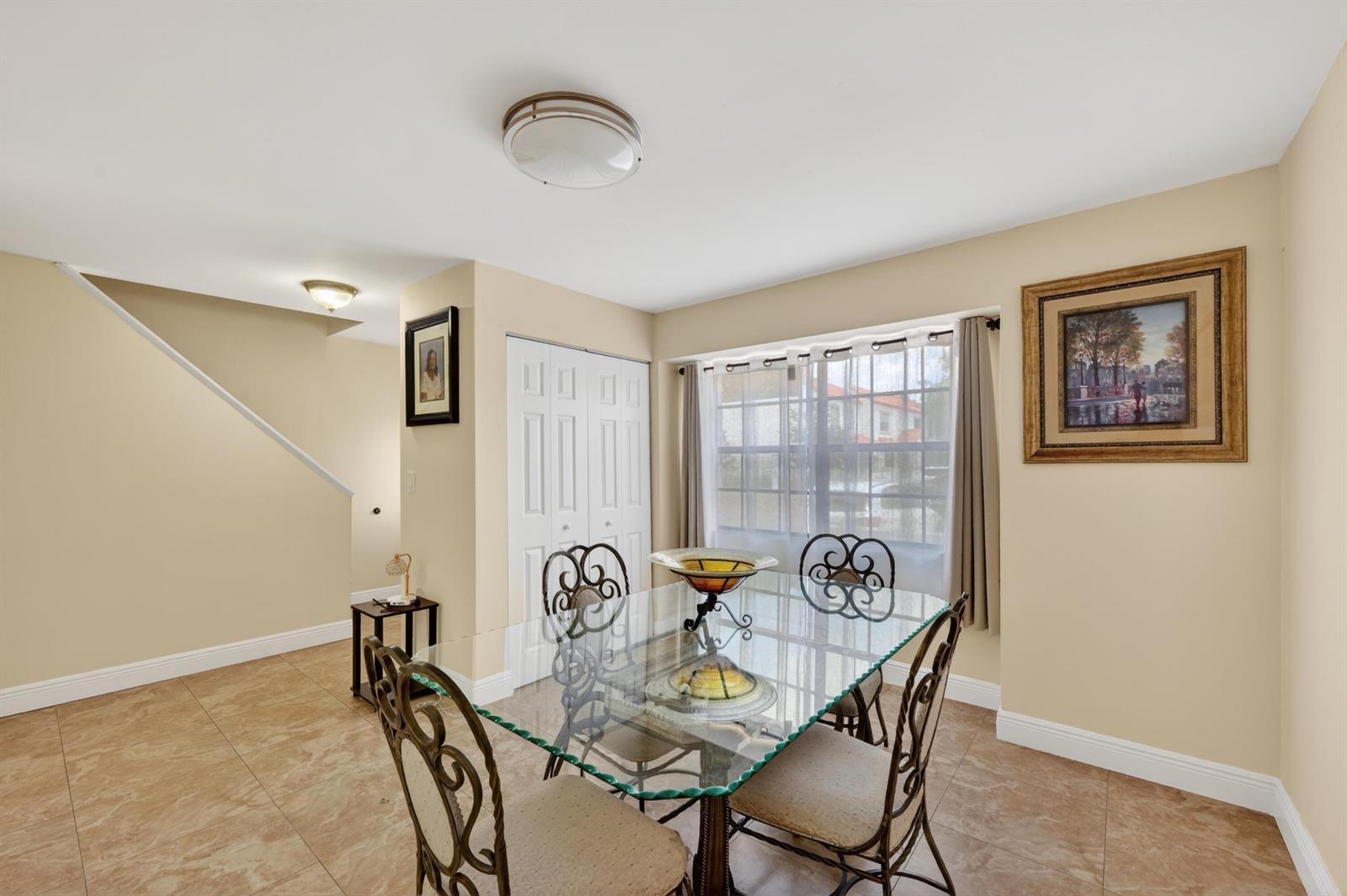 A dining room features a glass-topped table, metal chairs, tile flooring, and a window — 9409 NW 42nd Street, Sunrise FL 33351, SUNRISE, FL