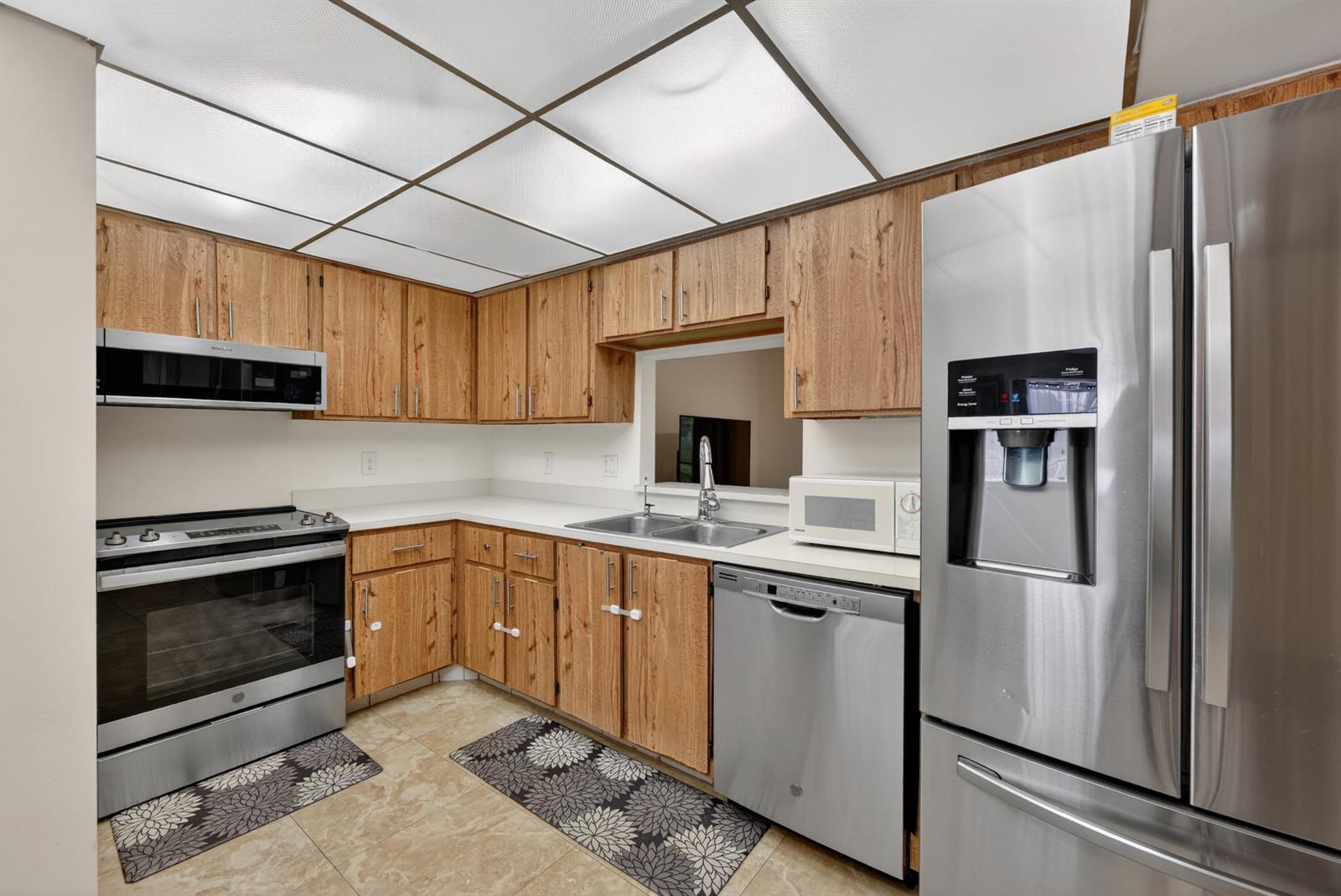 A kitchen features wood cabinets, stainless steel appliances, white countertops, and a drop ceiling — 9409 NW 42nd Street, Sunrise FL 33351, SUNRISE, FL