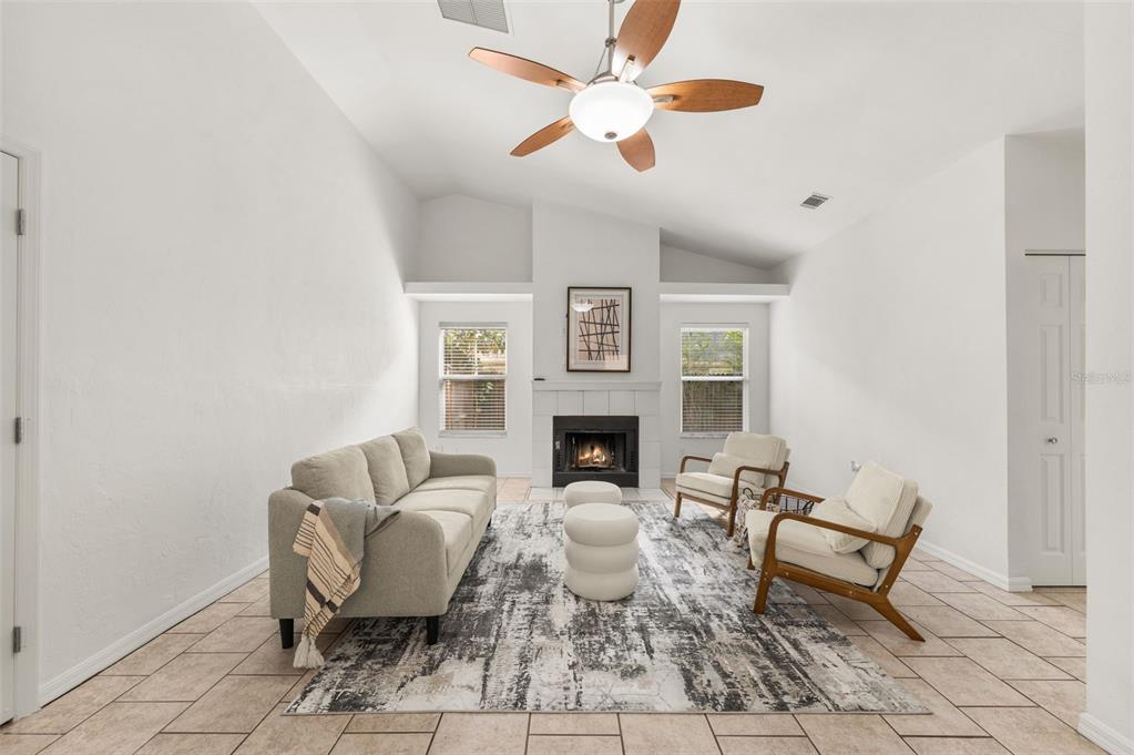 A living room features a fireplace, vaulted ceiling, tile floors, and a neutral furniture arrangement — 6220 SW 81ST STREET, GAINESVILLE, FL