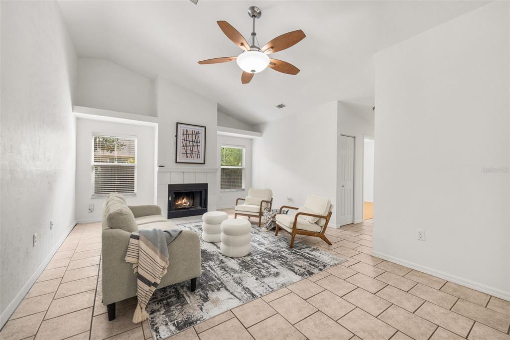 A living room features a fireplace, tiled floors, a vaulted ceiling, and a ceiling fan — 6220 SW 81ST STREET, GAINESVILLE, FL