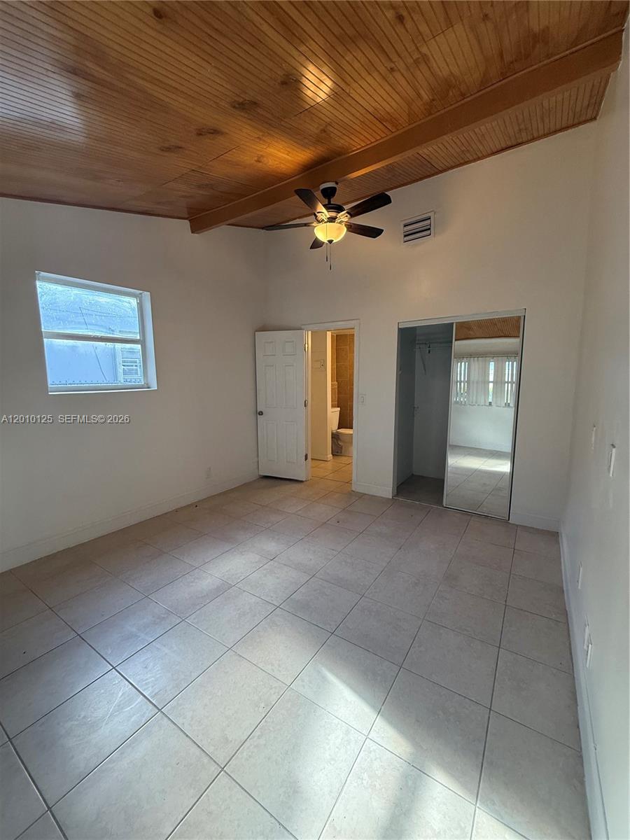 A bedroom features a wood-paneled vaulted ceiling, tile flooring, a ceiling fan, and an attached bathroom — 1619 Shenandoah St, Hollywood FL 33020, HOLLYWOOD, FL
