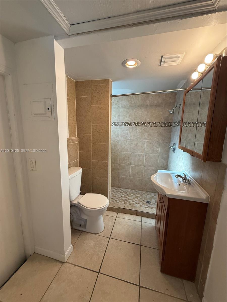 A bathroom features a tiled shower, a pedestal sink, and a toilet on tiled floors — 1619 Shenandoah St, Hollywood FL 33020, HOLLYWOOD, FL