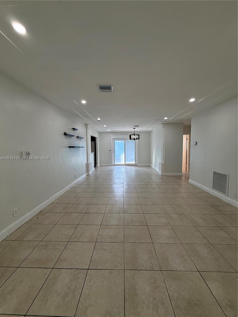 An empty, rectangular room features light-colored tile flooring, recessed lighting, and white walls — 1619 Shenandoah St, Hollywood FL 33020, HOLLYWOOD, FL