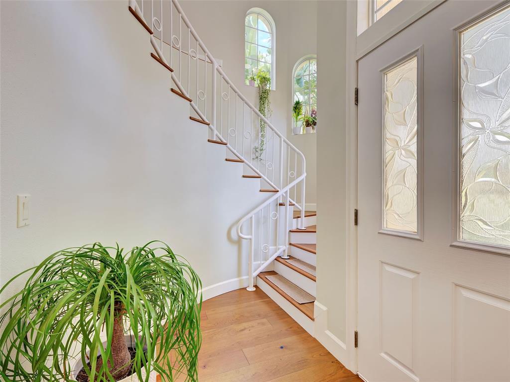 A bright entryway features a curved white staircase with wooden treads and a potted plant — 5026 HANGING MOSS LANE, SARASOTA, FL