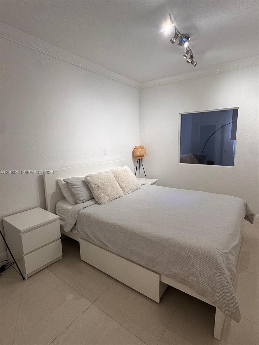 A bedroom features a white bed frame, two nightstands, and a ceiling track light fixture — 2301 Collins Ave # 427, Miami Beach FL 33139, MIAMI BEACH, FL