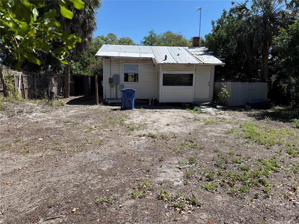 A small, single-story house with light-colored siding and a metal roof sits on a dirt lot — 2007 43RD STREET S, GULFPORT, FL