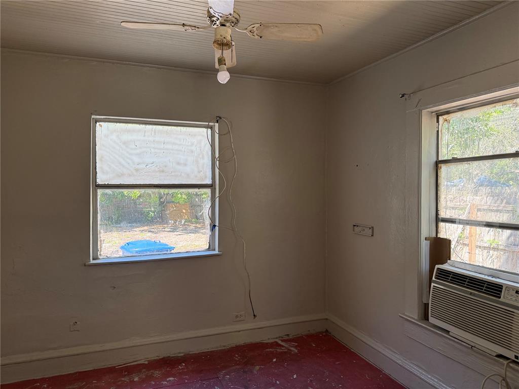 An empty room features a ceiling fan, two windows, and a window-mounted air conditioning unit — 2007 43RD STREET S, GULFPORT, FL