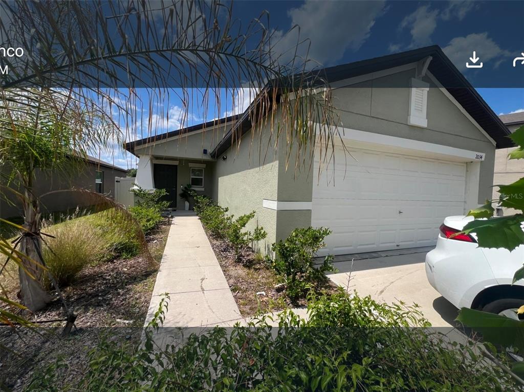 A single-story house with a white garage door, a concrete walkway, and green landscaping — 2034 OLD PASTURE LANE, LAKELAND, FL