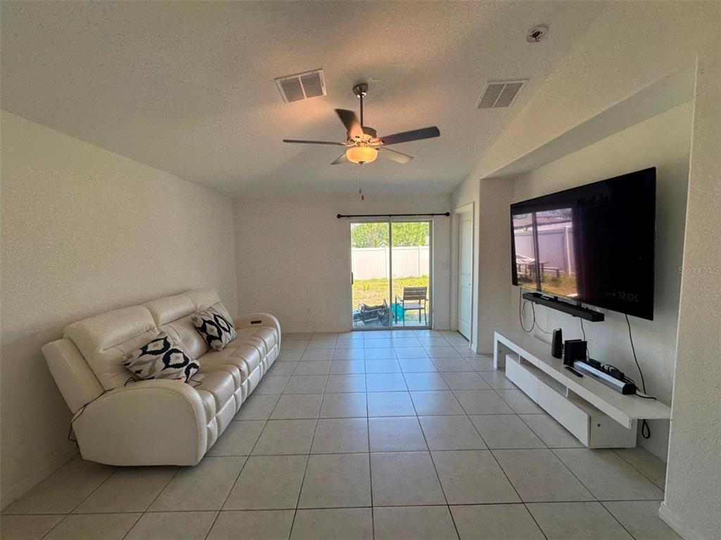 A living room features white tile floors, a white leather sofa, and a wall-mounted television — 2034 OLD PASTURE LANE, LAKELAND, FL