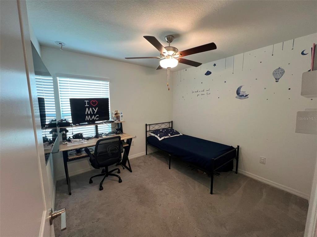 A bedroom features a twin bed, a desk with a computer, and a ceiling fan — 2034 OLD PASTURE LANE, LAKELAND, FL