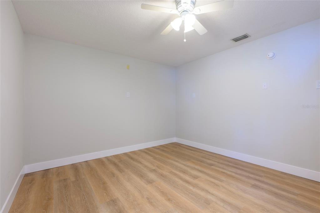 An empty room with light gray walls, white baseboards, and wood-look flooring — 1612 1ST ST, INDIAN ROCKS BEACH, FL