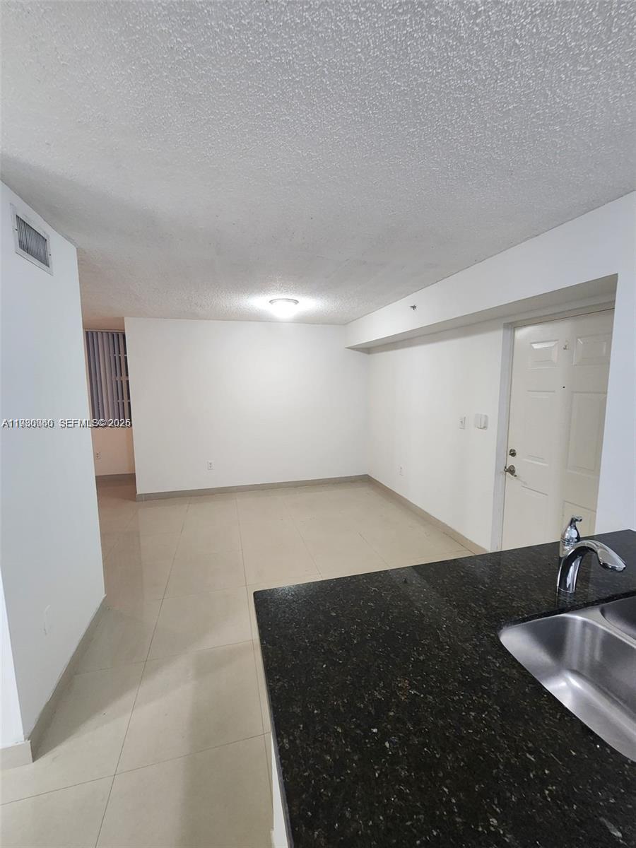 A kitchen counter with a sink overlooks an empty room with white walls and tile — 4560 NW 107th Ave # 12, Doral FL 33178, DORAL, FL