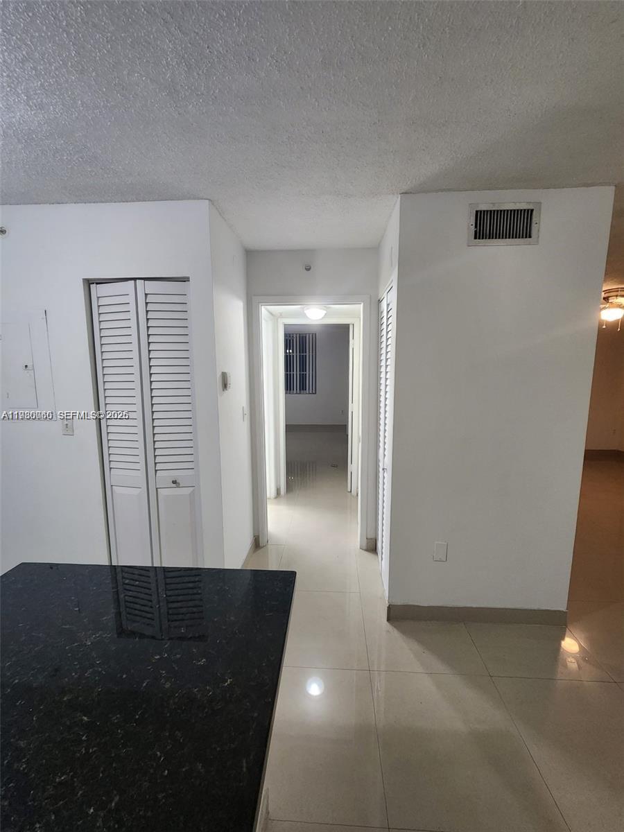 A hallway with white walls and tiled floors leads to a bedroom through a doorway — 4560 NW 107th Ave # 12, Doral FL 33178, DORAL, FL
