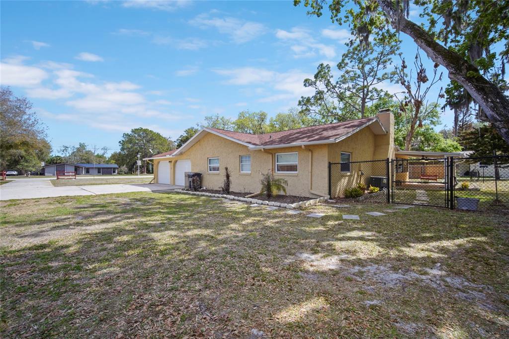 A yellow stucco house with a two-car garage and a fenced backyard — 3065 KNOX MC RAE DRIVE, TITUSVILLE, FL