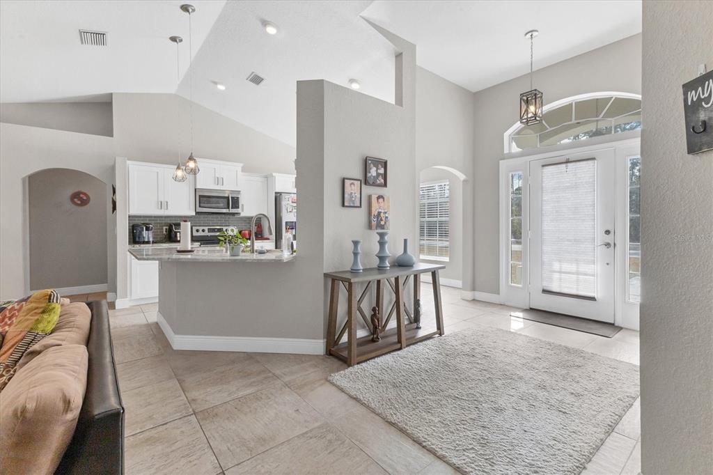 An open-concept living area features a kitchen with white cabinets, tile flooring, and an entryway — 7380 MERONI BOULEVARD, NORTH PORT, FL