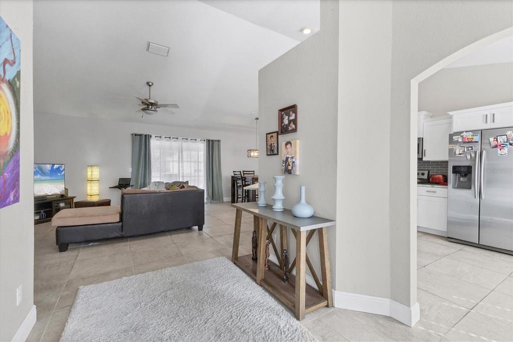 A view from an entryway looking into a living room and kitchen with tiled floors — 7380 MERONI BOULEVARD, NORTH PORT, FL