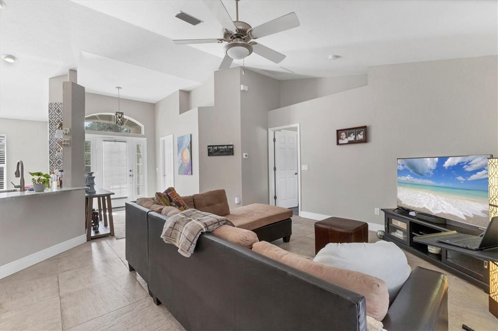 A living room features a sectional sofa, a television on a stand, and vaulted ceilings — 7380 MERONI BOULEVARD, NORTH PORT, FL